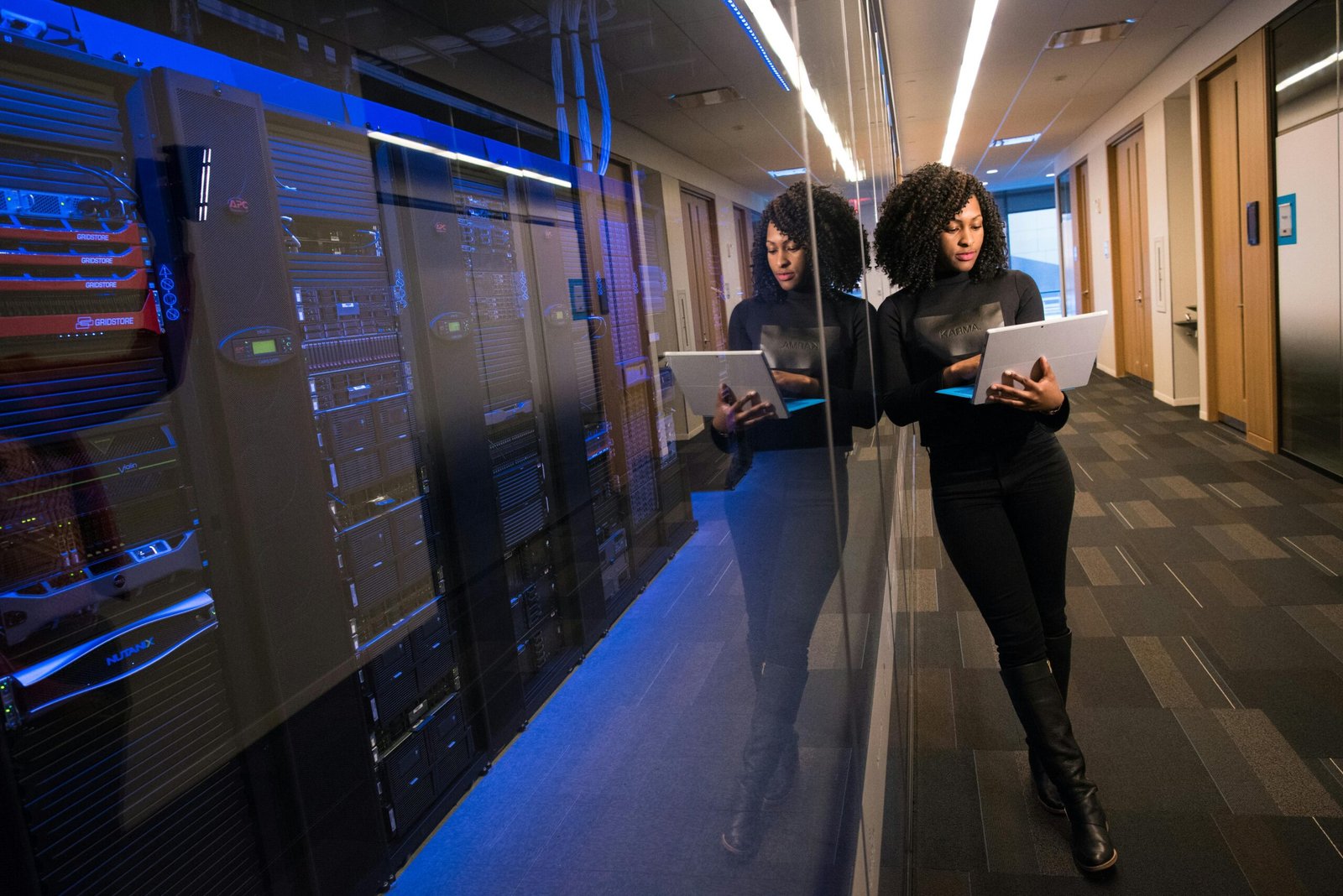 service-1 A woman using a laptop navigating a contemporary data center with mirrored servers.